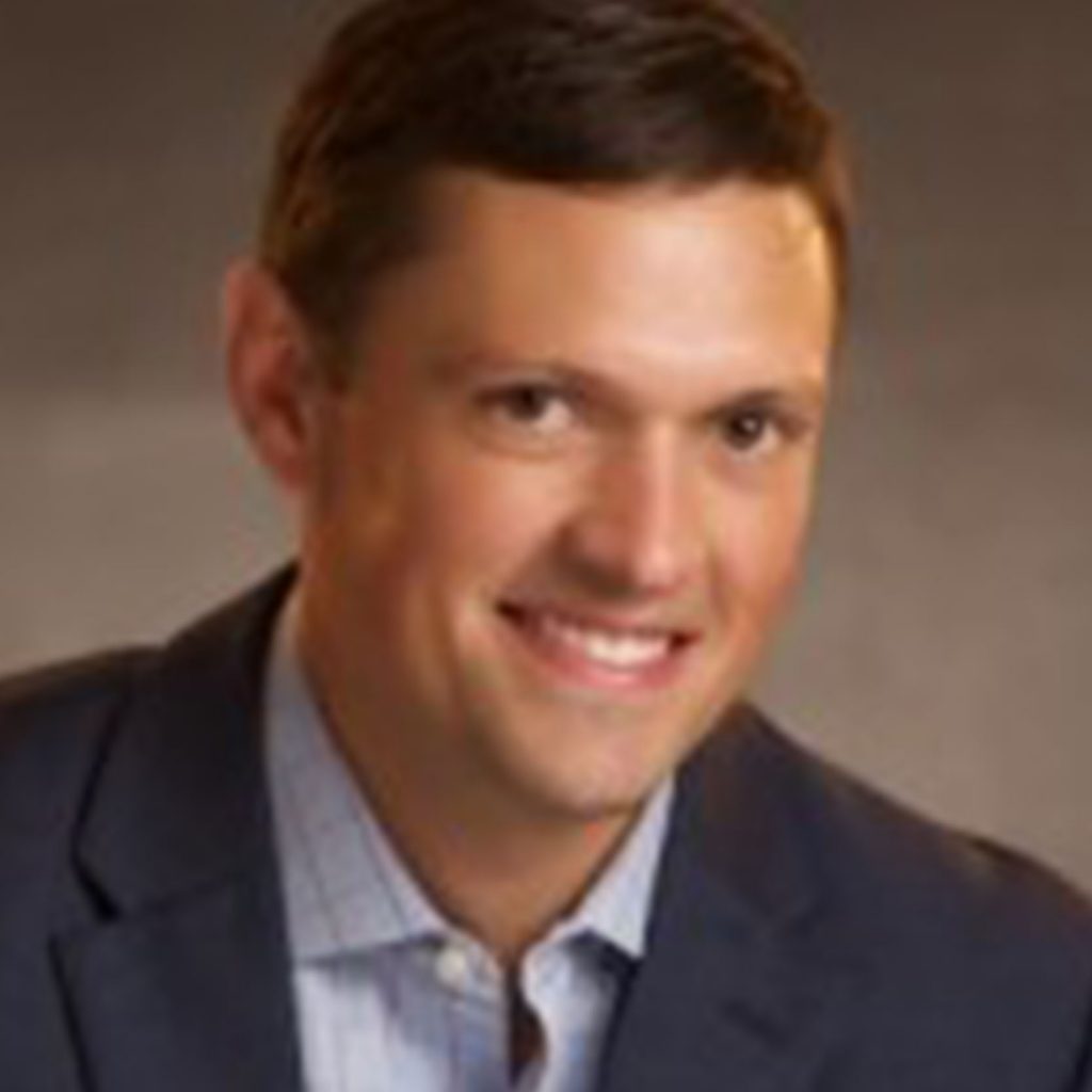 A Man Wearing A Suit And Tie Smiling At The Camera